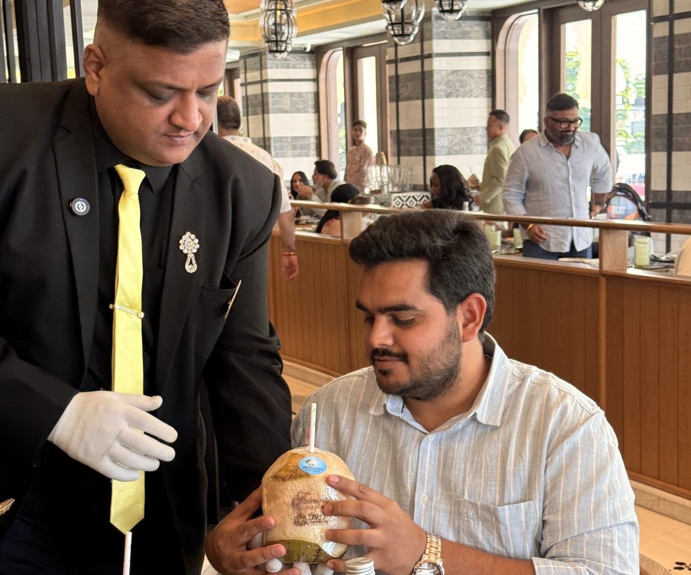 CocoBoy serving a fresh coconut at a guest table